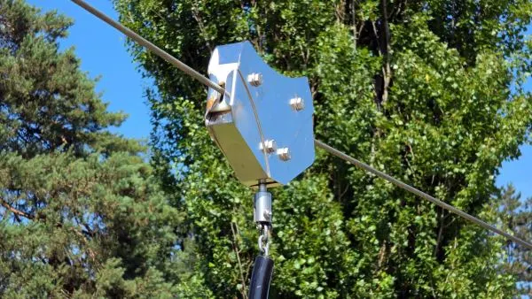 Zipline trolley mechanism sitting on a silver steel cable